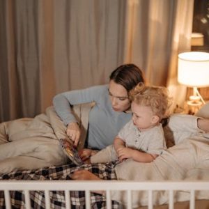 Father and mother reading to their child in bed during nighttime for a cozy bedtime story.